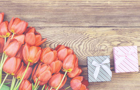 Bouquet of Fresh Orange Tulip Flowers on Top of Wooden Table with Two Gift Boxes, Captured in High Angle View.の写真素材