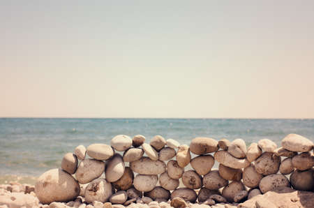 Artistic rock wall on a sandy beach made from balancing natural irregular shaped rocks on top of one another without mortar in a dry-stone formationの写真素材
