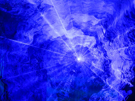 Blue spotlight shining through a haze of swirling smoke creating an interesting abstract patternの写真素材