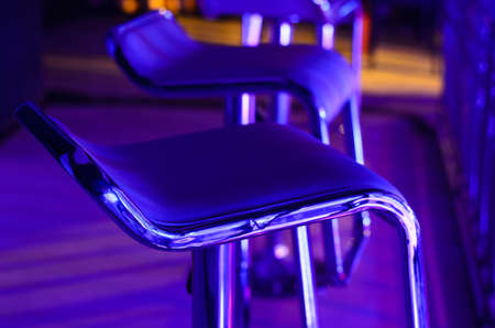 Detail of Empty Bar Stool Lit in Purple Blue Light at Night Club or Barの写真素材