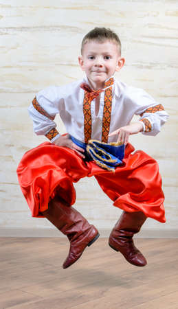 Ukrainian talented child performing a traditional dance move with a leap in mid air while wearing folk costume during a cultural artistic representationの写真素材