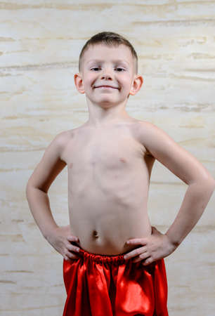 Full Length Portrait of Young Expressionless Boy Posing in Studio with Hands on Hips, Shirtless Male European Dancer Wearing Traditional Red Dance Pants and Bootsの写真素材