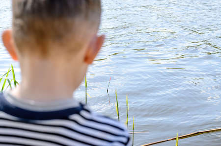 Close up Rear View of a Young Male Kid Fishing at the River Alone Using a Fishing Rod on a Very...