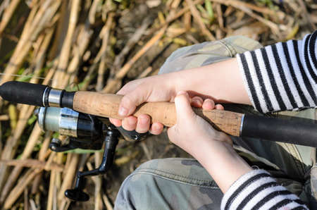 Young boy fishing with a spinning reel and rod, close up of his hands on the cork handleの写真素材
