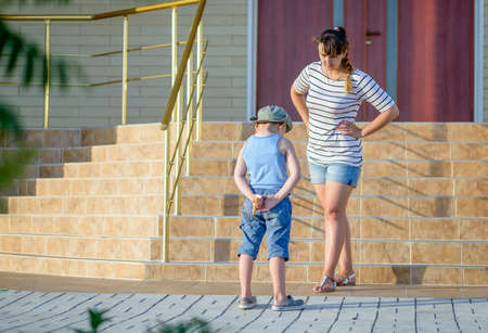 Angry Mother Scolding Son in front of Home - Young Boy Hiding Ice Cream Cone Behind Back and Getting...
