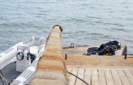 Small Fishing Boat Tied Up Next to Dock with Pile of Scuba Diving Equipment Drying in Sun, with Perspective View Down Railingの写真素材