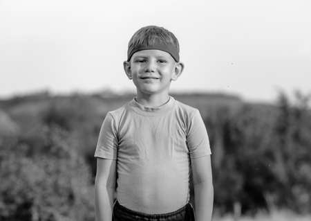 Half Body Shot of a Cute White Young Boy with Red Warrior Headband, Smiling at the Camera Against...