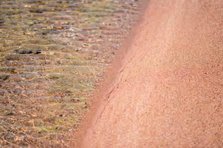 Idyllic sandy beach with scattered rocks and crystal clear sparkling water for an idyllic summer holiday destinationの写真素材