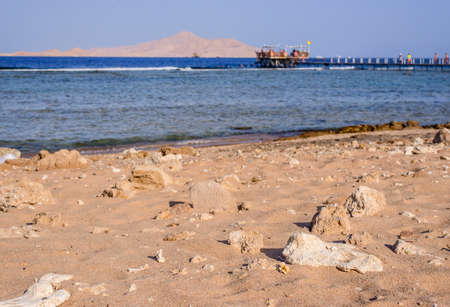 Tropical bay with a wooden jetty or pier leading out over the shallow tidal water to the edge of the channel and deeper water with wooden huts for tourists to enjoy their summer vacationの写真素材