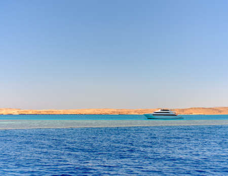 Pleasure boat or tour boat moored off an offshore shallow sand bank and reef for skin diving in a calm blue tropical ocean on a summer vacationの写真素材