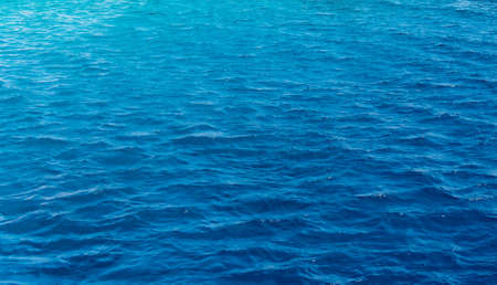 Background texture of a calm deep blue ocean with ripples on the surface of the seawater, full frameの写真素材