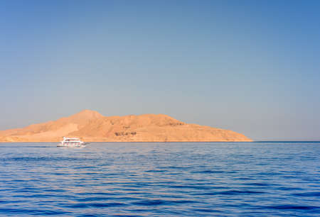 Pleasure boat or tour boat moored off an offshore shallow sand bank and reef for skin diving in a calm blue tropical ocean on a summer vacationの写真素材