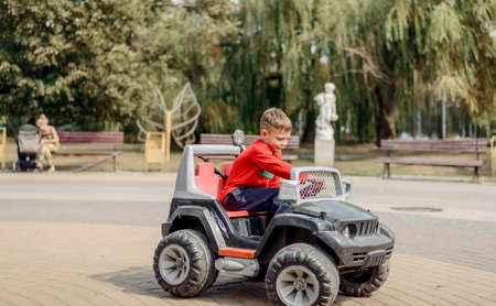 Cute little boy driving a large mechanical toy truck turning the steering wheel with a look of...