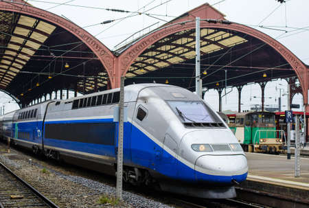 Modern engine and coaches of a passenger train waiting alongside a platform at a station for passengers to board in a travel or commuting conceptのeditorial素材