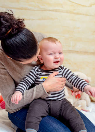 Loving Mom Soothing and Hugging her Crying Cute Baby While Looking Away From the Camera.