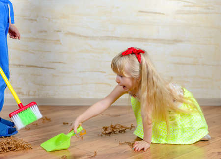 Little Boy and Girl Cleaning the Messy Stuff on the Floor at Home Together.の写真素材