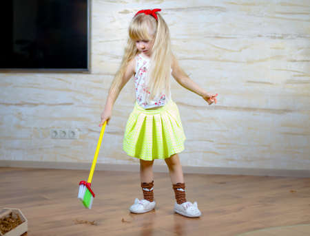 Full Length Shot of a Little Blond Girl Holding Broom, Doing Household Chores Alone Seriouslyの写真素材