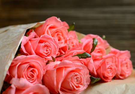 Close up on bundle of beautiful stemmed pink roses over old wooden table at angleの写真素材