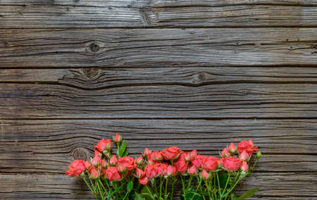 Top down view on large rose bundle in bottom half over weathered wooden table surface with copy spaceの写真素材