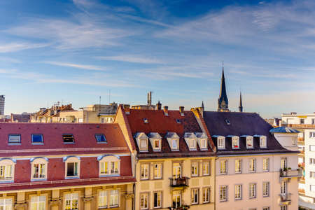 Row of three types of connected town homes under pretty skies with church bell tower spire in backgroundの写真素材