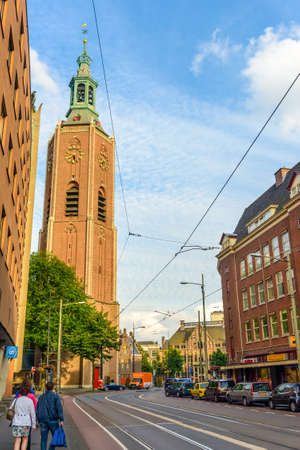 Hague, Netherlands - 28 July 2016:Pretty European city with clock tower near street and parked cars as shoppers walk towards itのeditorial素材