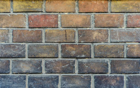 Old weathered brick wall background texture with rough irregular clay bricks in an assortment of hues in a full frame vertical viewの写真素材
