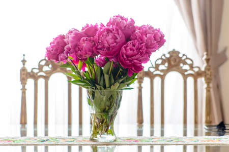 Shiny and reflective dining room table with floral centerpiece by ornate chairの写真素材