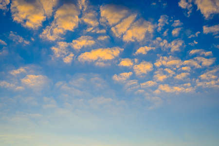Pretty fluffy orange clouds in a blue twilight sky at sunset with copy space below for nature or weather themed conceptsの写真素材