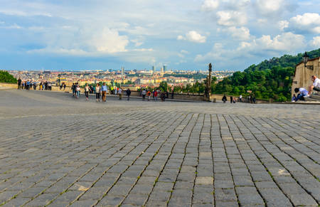 Scenic view of distant European city under billowy clouds as seen from cobblestone pedestrian boulevardの写真素材