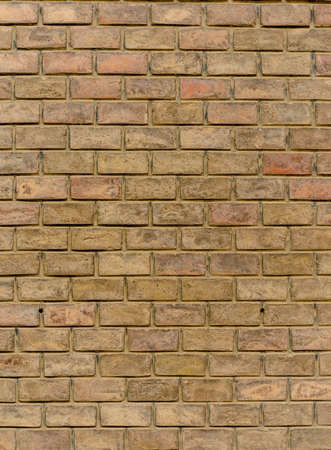 Old weathered brick wall background texture with rough irregular clay bricks in an assortment of hues in a full frame vertical viewの写真素材