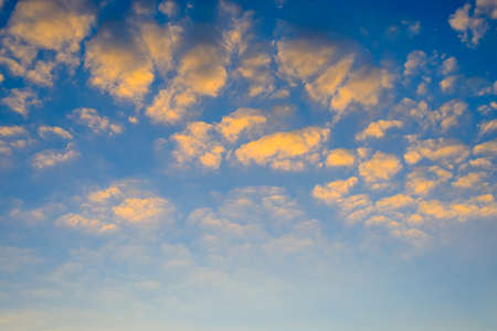 Pretty fluffy orange clouds in a blue twilight sky at sunset with copy space below for nature or weather themed conceptsの写真素材