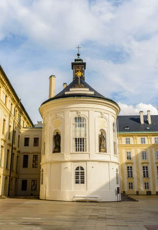Czech Republic, Prague, Historic round little tower with crucifix on top and large statues around it under sunny sky with scattered cloudsの写真素材