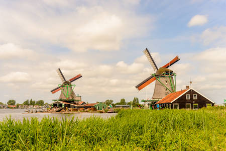 Traditional windmills on farm during summer with green buildings in large field under beautiful skiesの写真素材