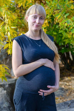 Attractive pregnant woman bonding with her unborn baby clasping her belly with a look of tenderness...