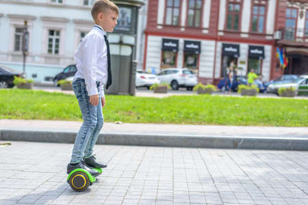 Stylish young boy riding a hover board in an urban park standing balancing on it facing the camera with a smileの写真素材
