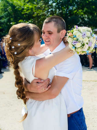 Loving newlyweds enjoy a romantic kiss hugging each other tightly outdoors in the sunshine in a close up viewの写真素材