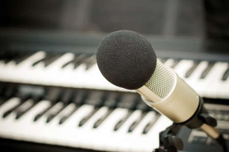 Close up on a microphone during recording session with a singer, piano in the backgroundの写真素材