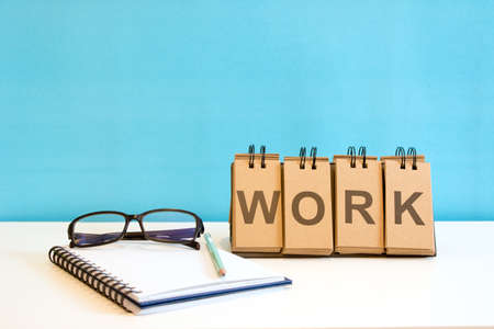 A book and standing paper with wording "WORK" on blue backgroundの写真素材