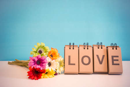 Flowers and label LOVE placed on the deskの写真素材