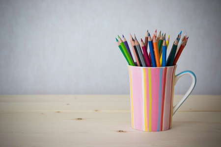 Still life color pencils in colorful cup on wooden table - vintage effect style pictureの写真素材
