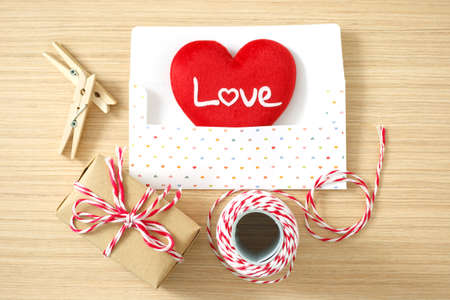 Envelope with red heart, peg, gift box, rope for valentine day on wooden table backgroundの写真素材