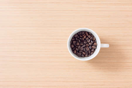 cup and coffee beans on wooden background with copy spaceの写真素材