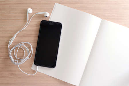 white earphone, smartphone, paper, book, note on wooden background with copy space - vintage effect...