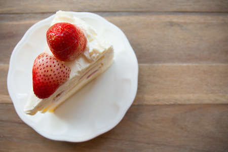 Slice of strawberry shortcake on wooden table with copy space.の写真素材