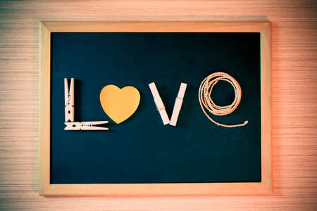 wooden cloth pegs, paper shape heart, rope sort the word LOVE on black board for valentine day - vintage effect style pictureの写真素材
