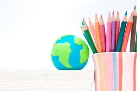 Earth globe made of clay on books stack and color pencil in colorful cup. Environmental awareness and education conceptの写真素材