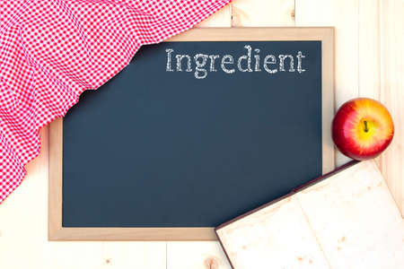 Open recipe book on a blackboard with wording Ingredient a red checkered tableclothの写真素材