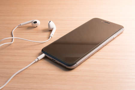 white earphones and smartphone on wooden background - vintage effect style picture