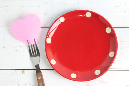 Empty note paper attached to fork and plate, on wooden background