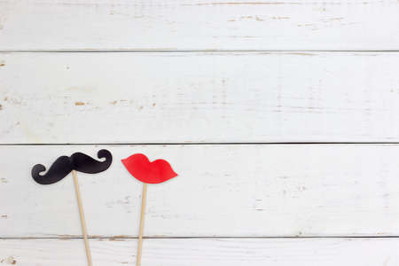 Paper heart shape fake mustaches in sticks in front of wooden white background. Wedding concept.の写真素材